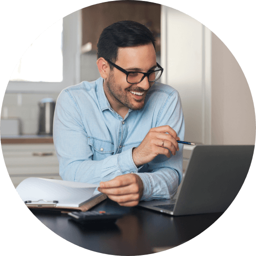 a man smiling and working on his laptop