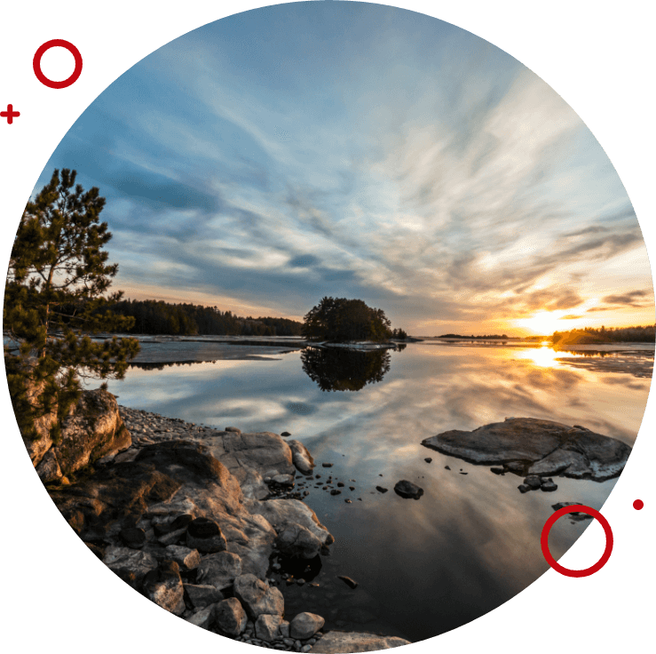Scenic lake view at sunset with rocky shoreline and trees reflecting on calm water  Title: Peaceful Lake View at Sunset