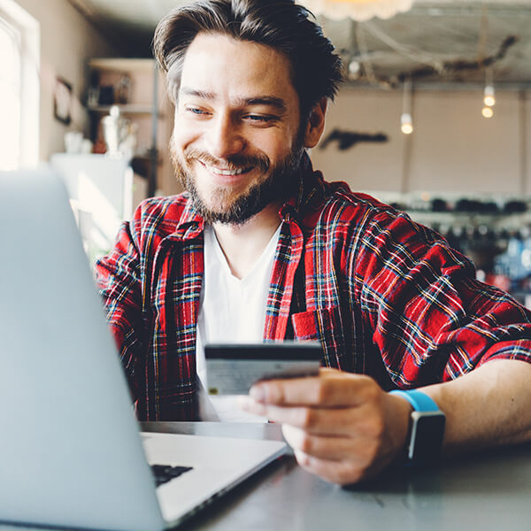 a man holding his credit card working on his laptop