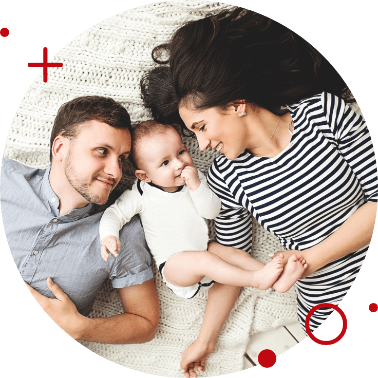 a mother and father laying on the floor with their baby in between them